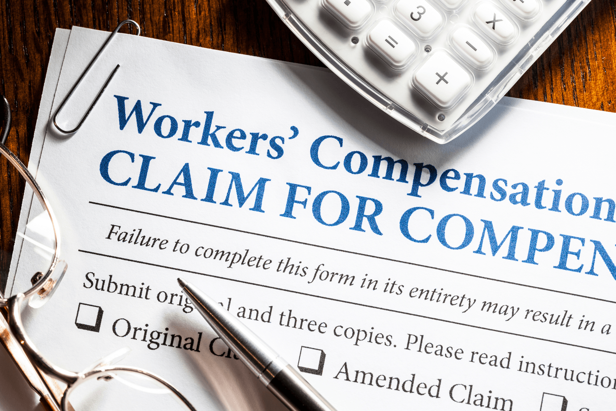 Workers' compensation claim form with a pen and glasses